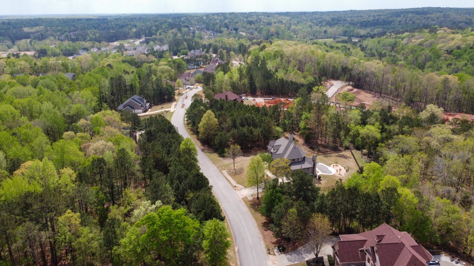 Aerial of a wooded community road — a development site under review